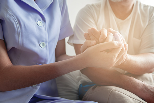 Close up of nurse holding hands of elderly woman